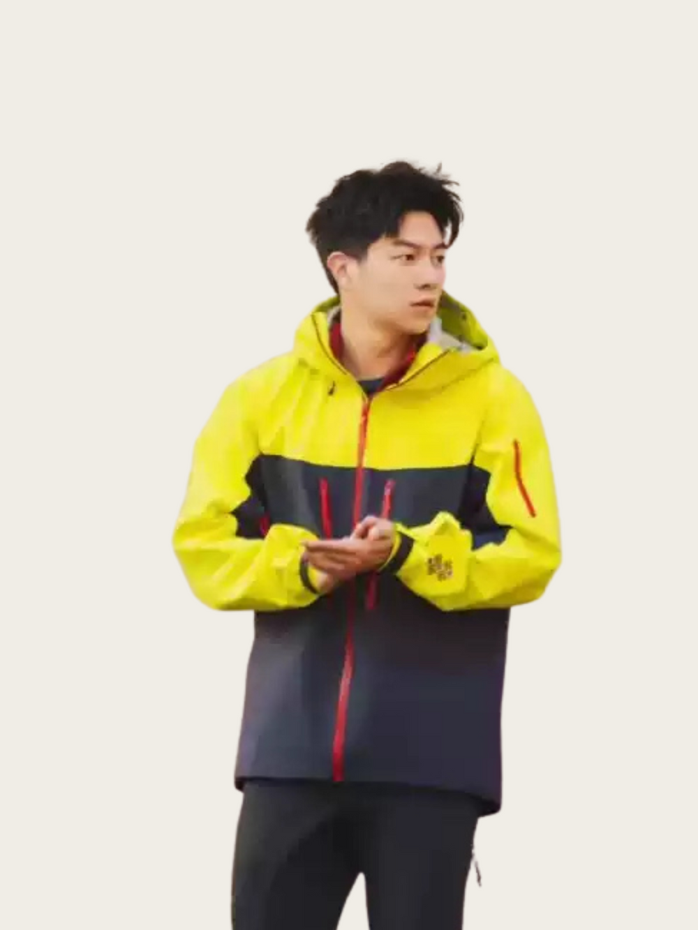 Person wearing a yellow and navy jacket with red accents on a light gray background