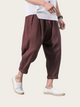 Person wearing brown harem pants and white shoes on a plain background
