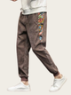 Brown pants with colorful side panels worn by a person on a white background
