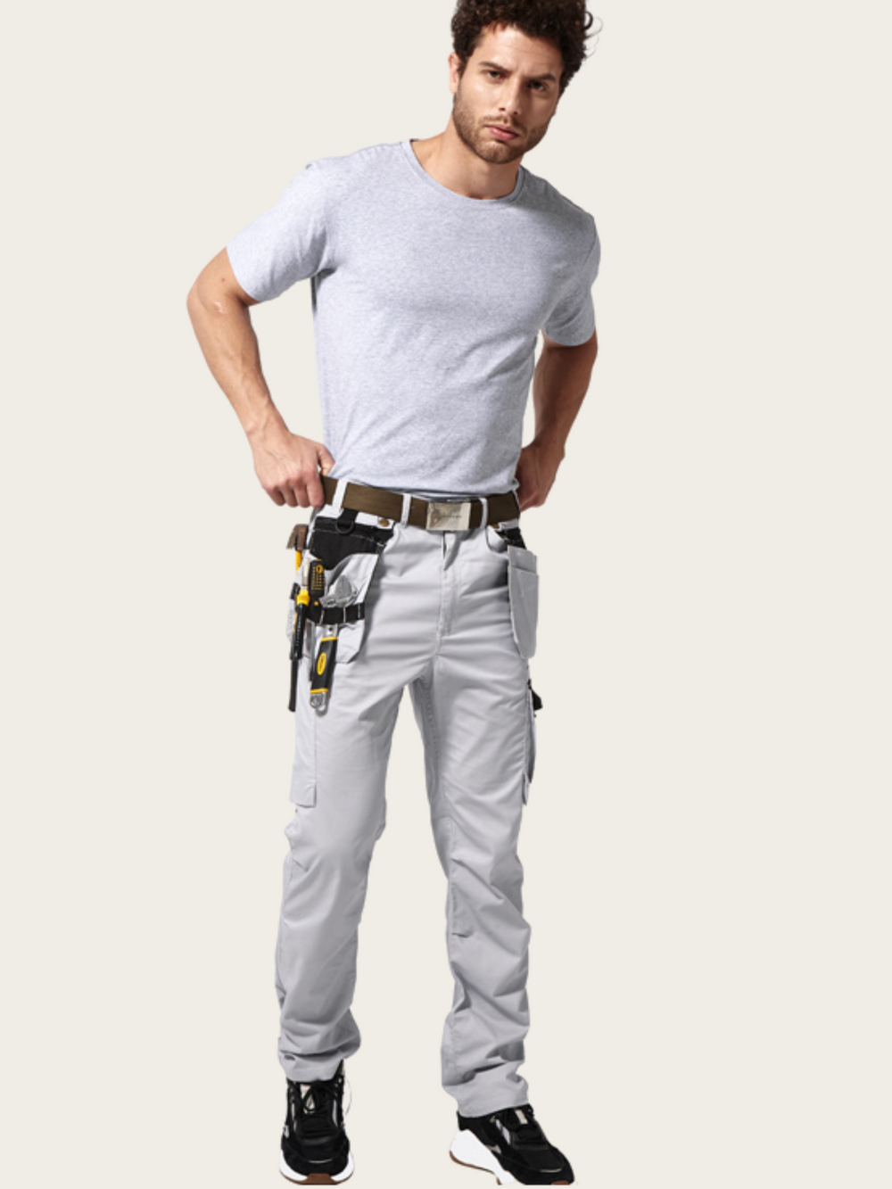 Man wearing light gray pants with tool belt on a white background