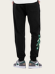 Black jogger pants with green design on a beige background