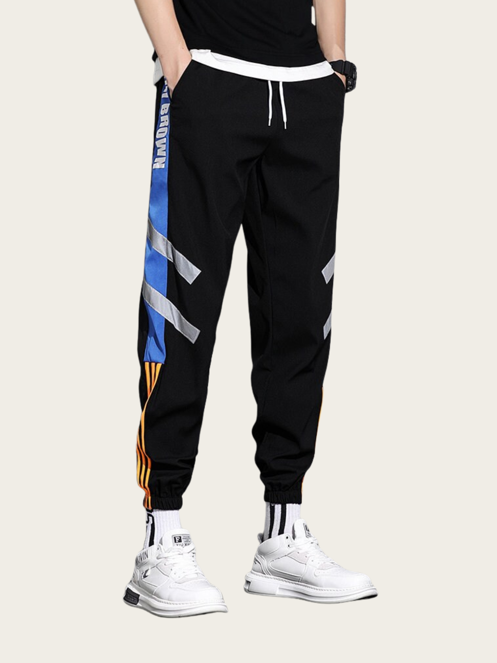 Black jogger pants with colorful side stripes worn by a person on a light background