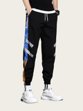 Black jogger pants with colorful side stripes worn by a person on a light background