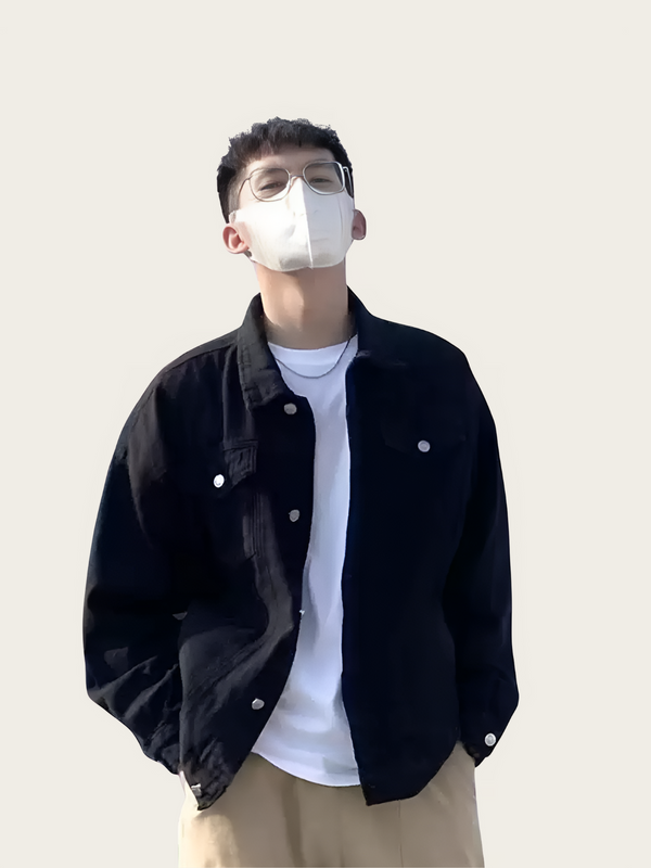 Person wearing a black jacket over a white shirt with a plain background