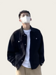 Person wearing a black jacket over a white shirt with a plain background