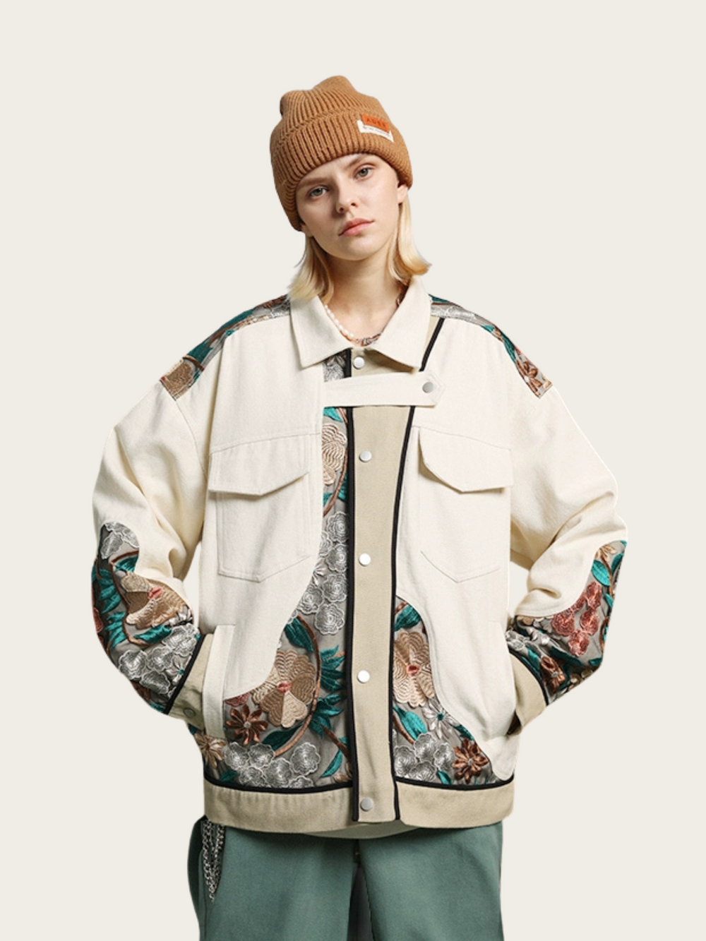Person wearing a stylish jacket with floral patterns and a brown beanie on a light background