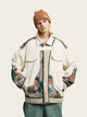 Person wearing a stylish jacket with floral patterns and a brown beanie on a light background