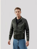 Man wearing a dark green jacket and blue jeans on a light gray background