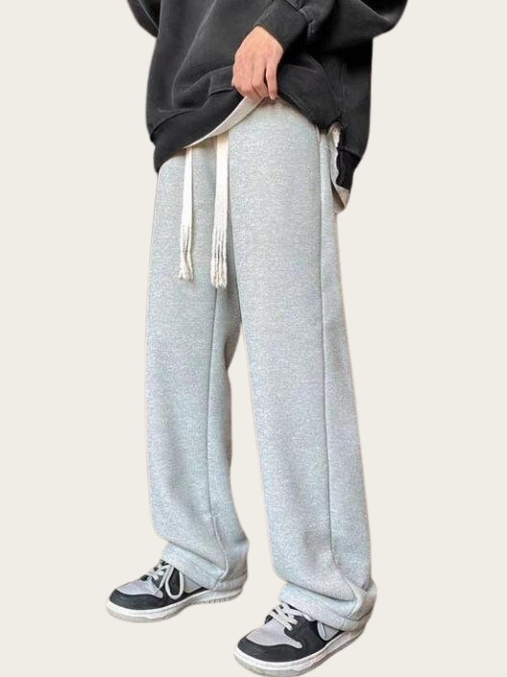 Person wearing gray sweatpants and black shoes on a plain background