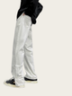 Person wearing silver reflective pants on a white background