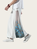 Person wearing a white top and wide-leg pants with a blue abstract pattern on a white background