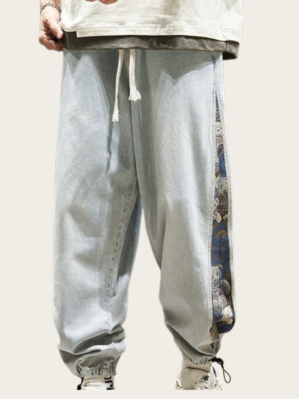 Light blue jogger pants with a patterned side panel on a plain background