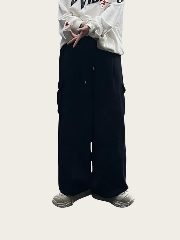 Person wearing a white sweatshirt with text and black pants on a light gray background