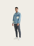 Man wearing a denim jacket and gray pants on a white background