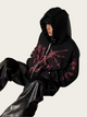 Person wearing a black hoodie with pink patterns on a white background