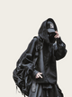 Person wearing a black hoodie and pants with a backpack on a plain background