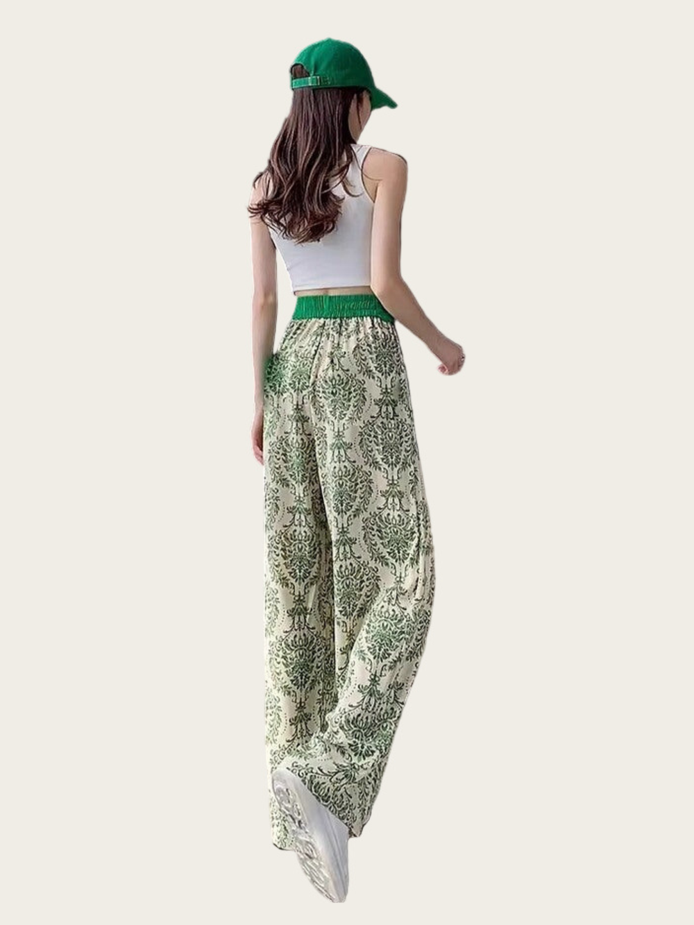 Woman wearing green patterned pants and a white top on a light background