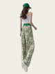 Woman wearing green patterned pants and a white top on a light background