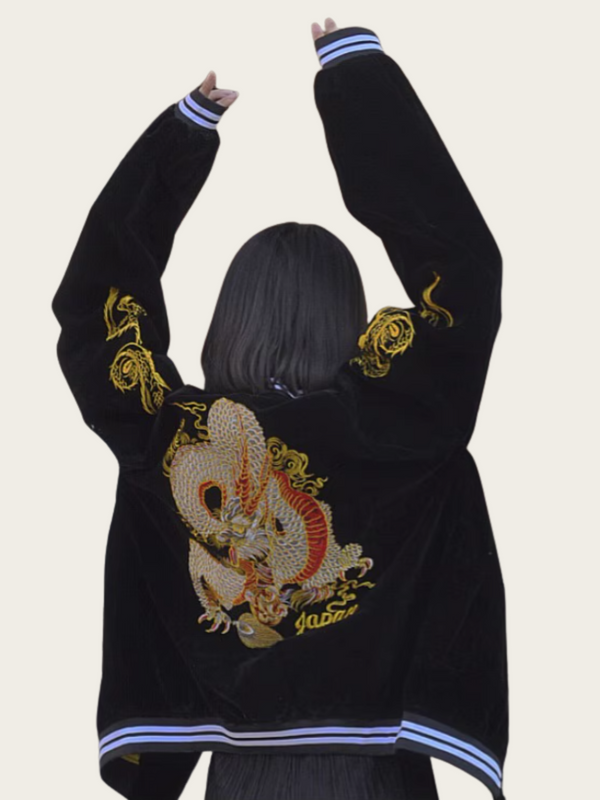 Person wearing a black jacket with gold dragon design on the back against a plain background