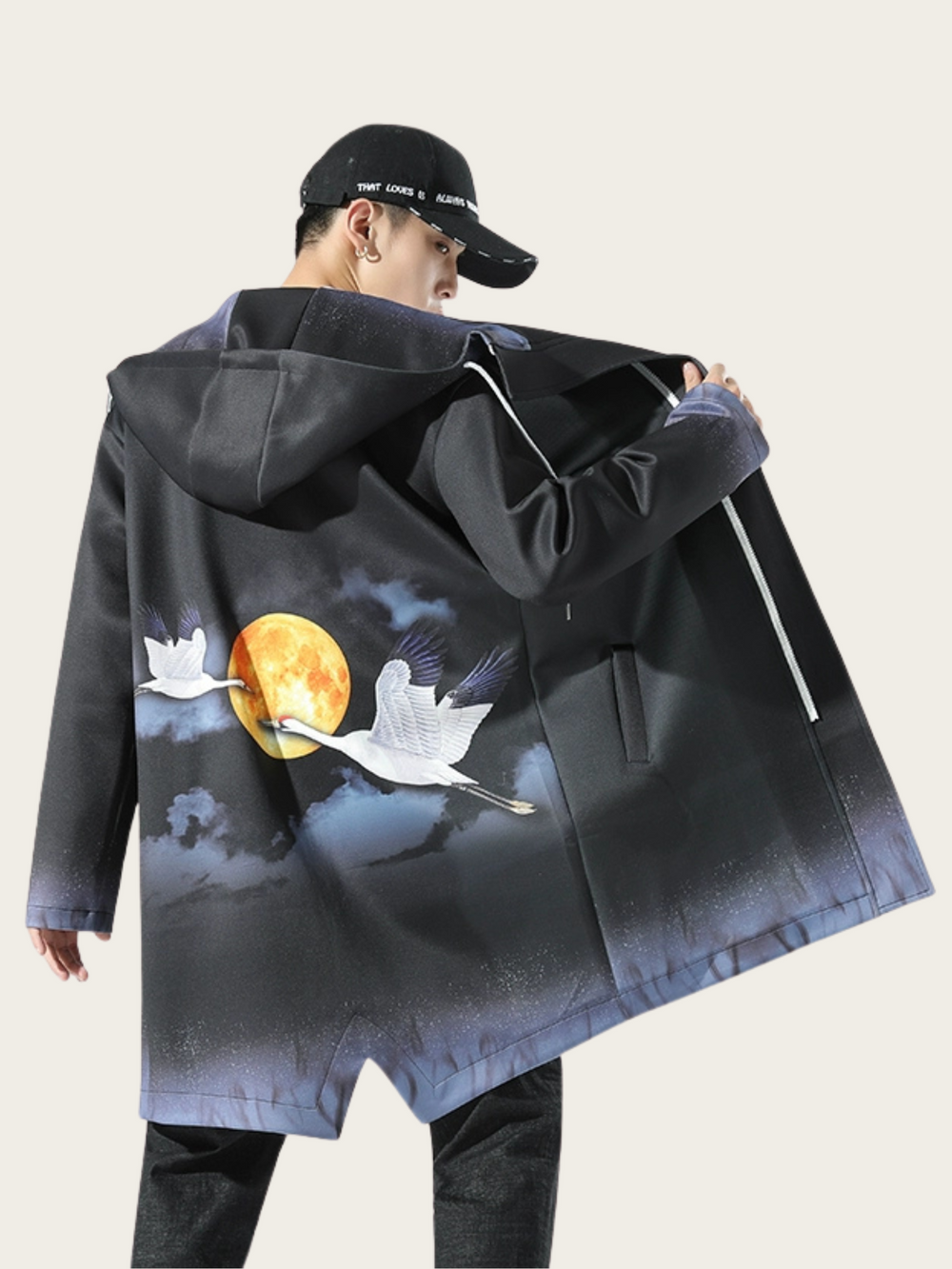 Person wearing a black coat with artistic design on the back, standing against a plain background