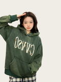 Person wearing a green hoodie with text on a plain background