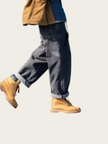 Person wearing dark jeans and tan boots on a light background