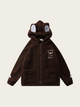 Brown teddy bear hoodie with white accents on a beige background