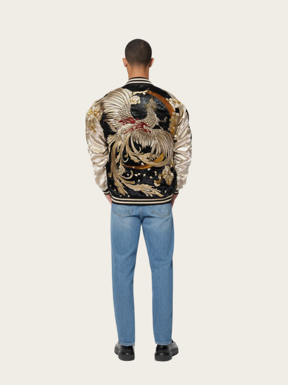 Person wearing a decorative jacket with a large bird design on a plain background