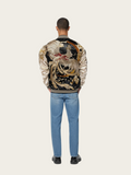 Person wearing a decorative jacket with a large bird design on a plain background