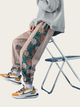 Person wearing floral pants and colorful sneakers sitting on a chair.