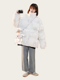 Person wearing a white puffer jacket with a small dog plush toy on a white background