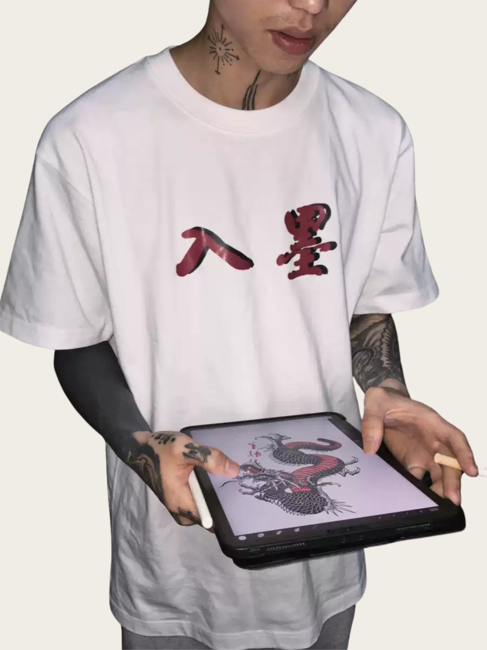 Person wearing a white t-shirt with red Chinese characters, holding a digital tablet with a dragon illustration.