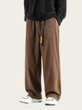 Brown corduroy pants worn by a person on a white background