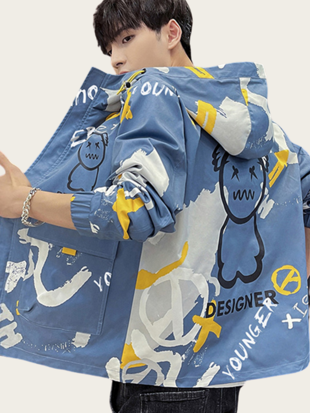 Person wearing a blue jacket with graphic designs on a plain background