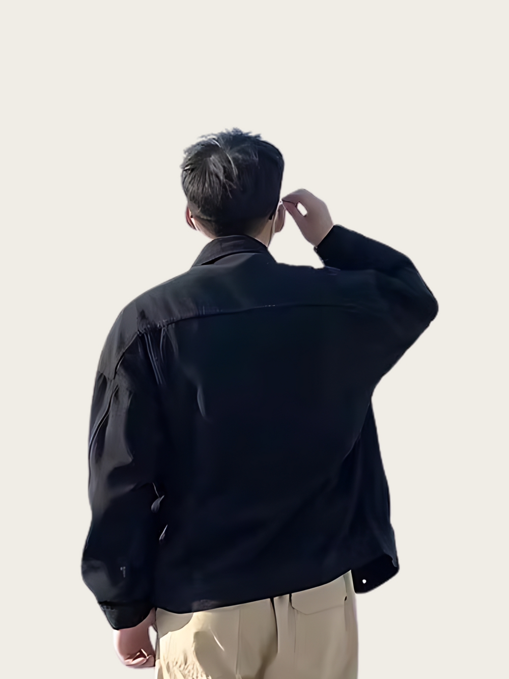 Person wearing a black jacket and beige pants against a plain background
