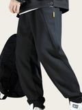 Person wearing black wide-leg pants with a backpack on a light background