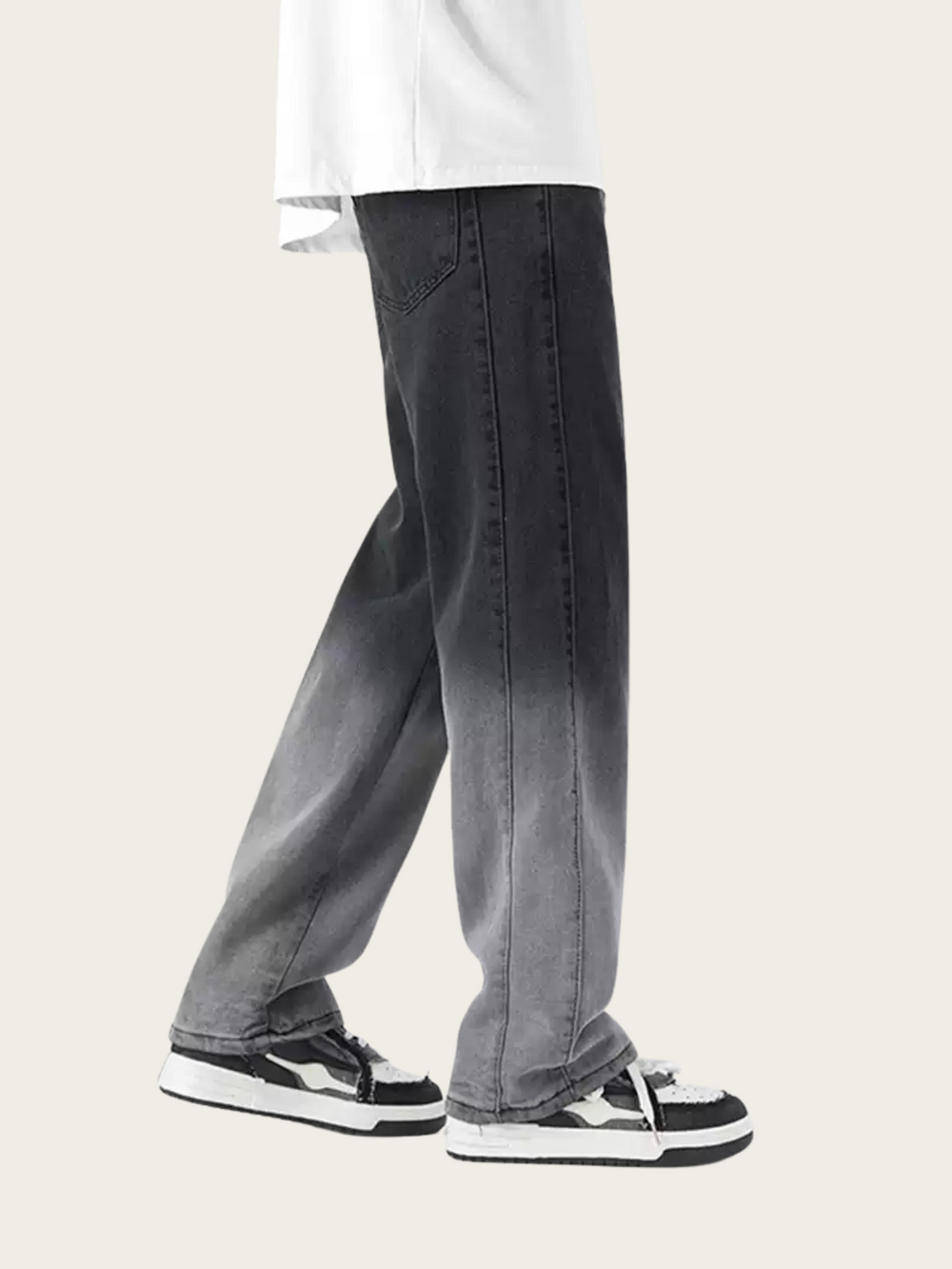 Person wearing gray jeans and white sneakers on a plain background