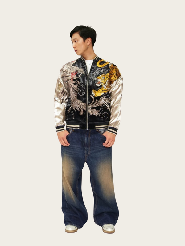 Person wearing a stylish jacket with dragon design and blue jeans on a white background
