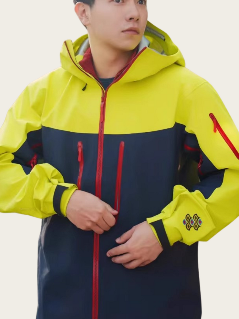Person wearing a yellow and navy jacket with red accents on a white background