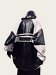Person wearing a black and white jacket with a logo on the back against a light gray background