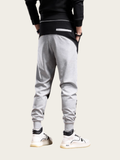 Person wearing gray jogger pants with a black top on a white background