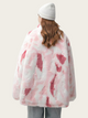 Person wearing a pink and white patterned coat against a plain background