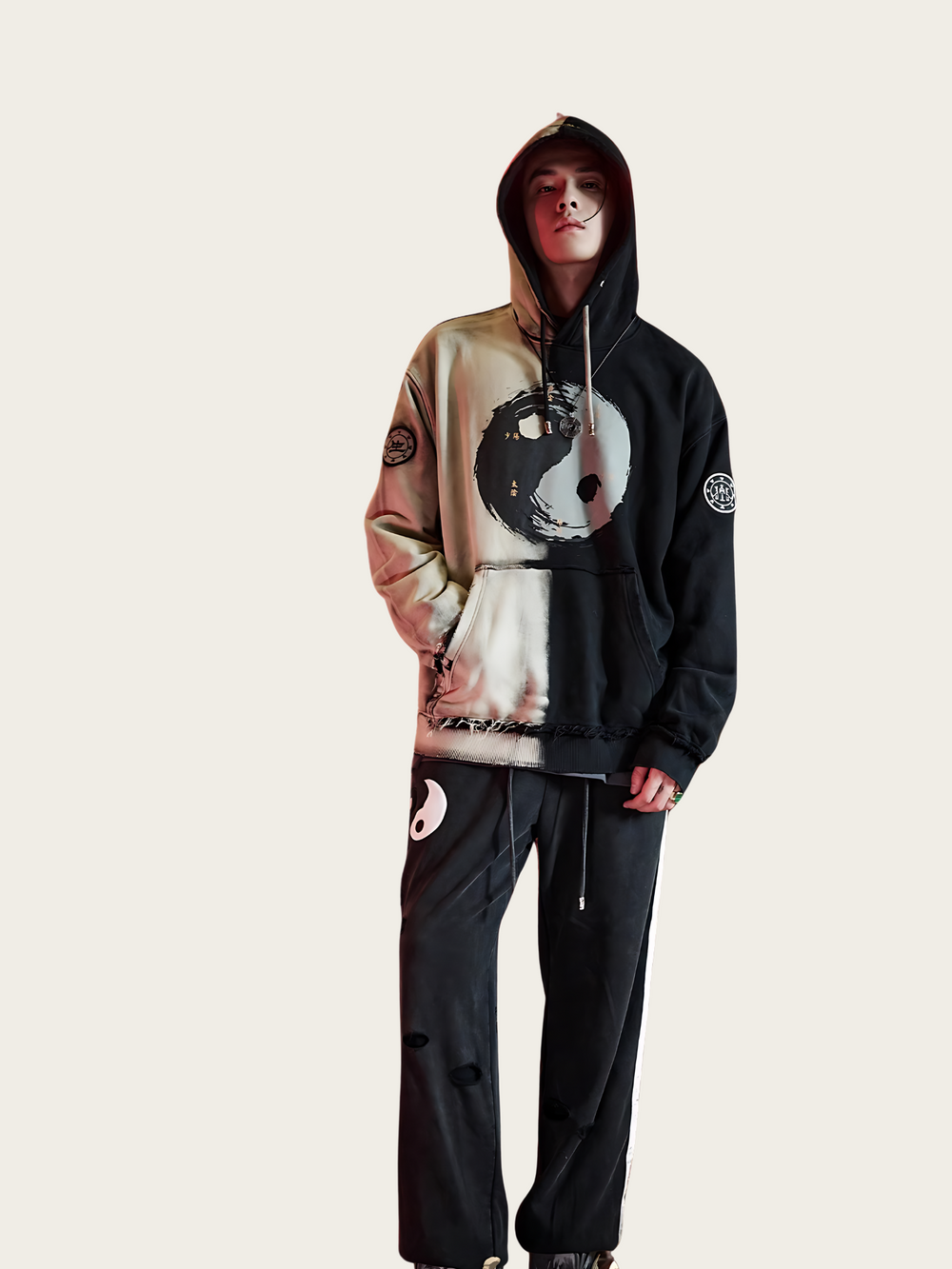 Person wearing a black and beige hoodie with a graphic design on a plain background