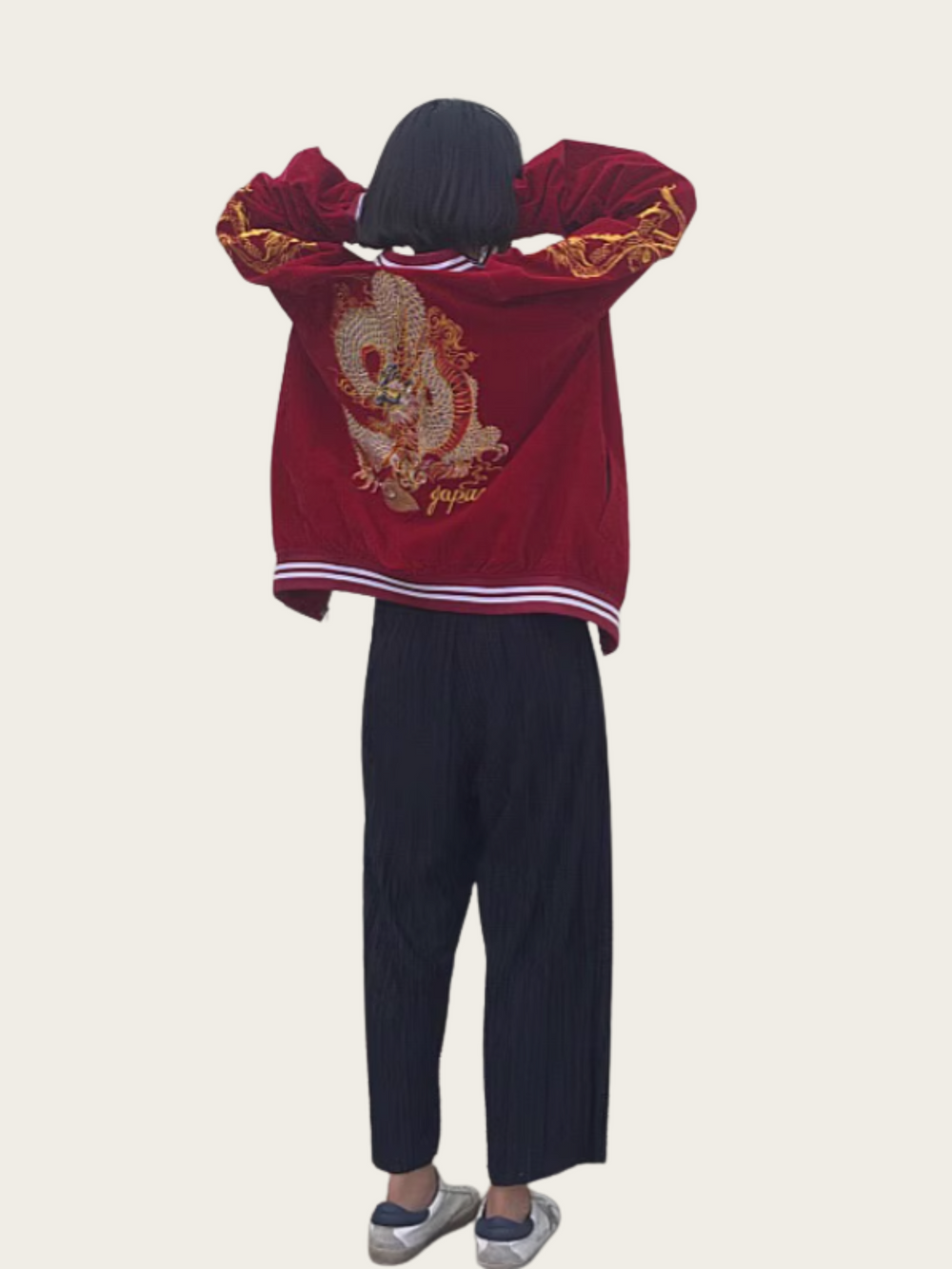 Person wearing a red embroidered jacket and dark pants on a beige background