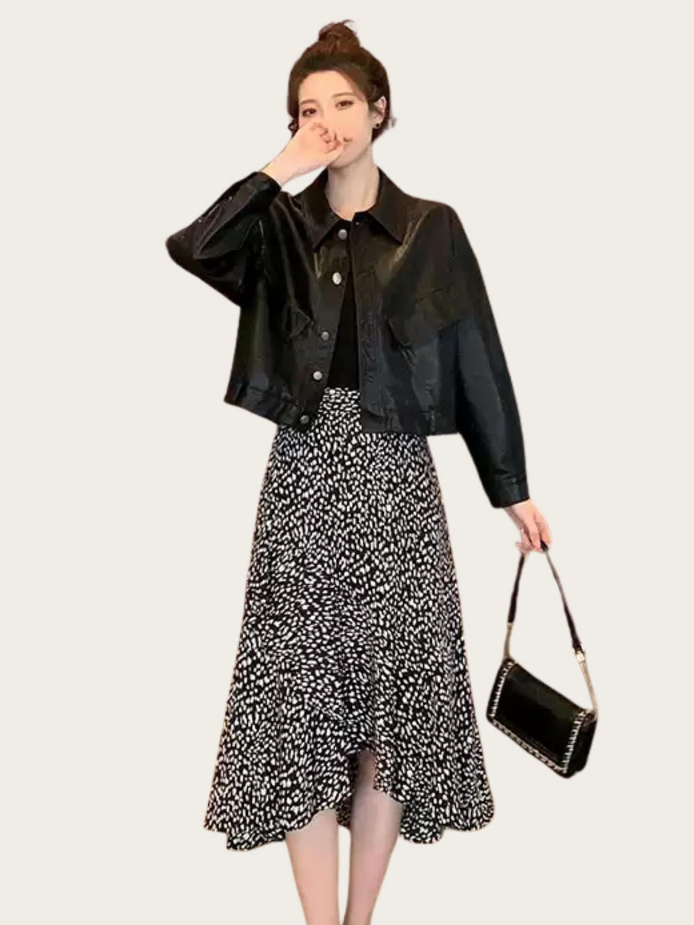 Woman wearing a black leather jacket and patterned skirt on a white background