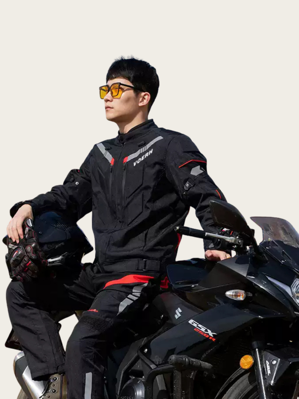 Person wearing a black motorcycle suit sitting on a black motorcycle with a neutral background