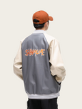 Person wearing a gray and beige varsity jacket with 'SAHMOCM' on the back, standing against a plain background.