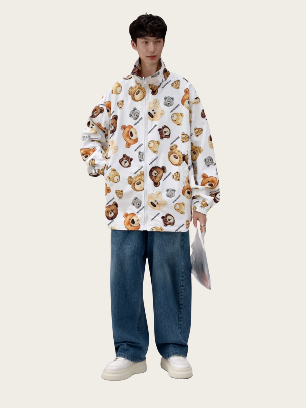 Person wearing a white jacket with bear pattern and blue jeans on a white background