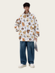Person wearing a white jacket with bear pattern and blue jeans on a white background