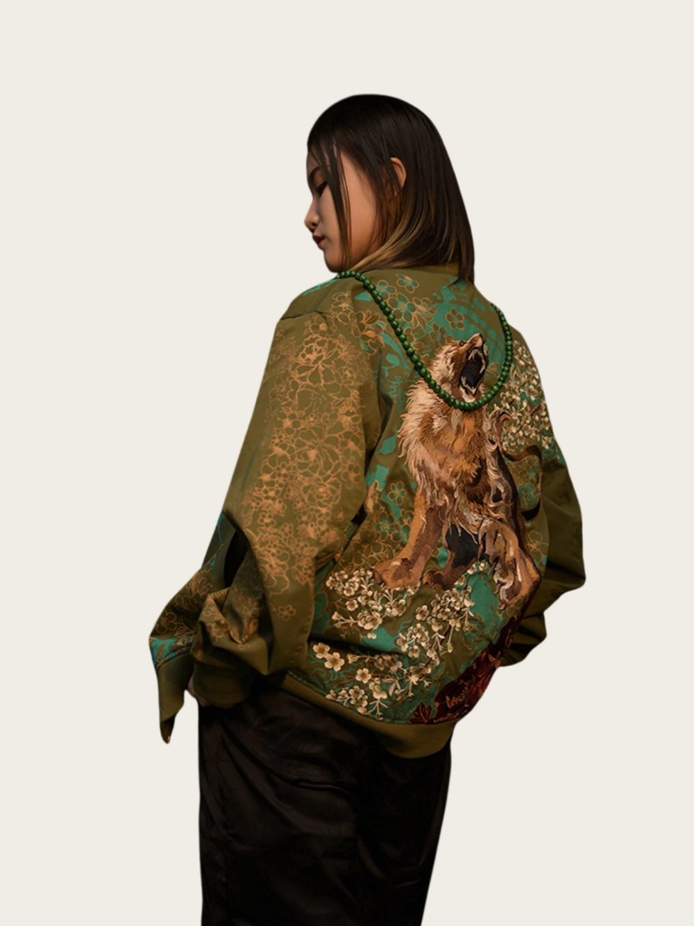 Person wearing a green patterned shawl with animal designs on a plain background